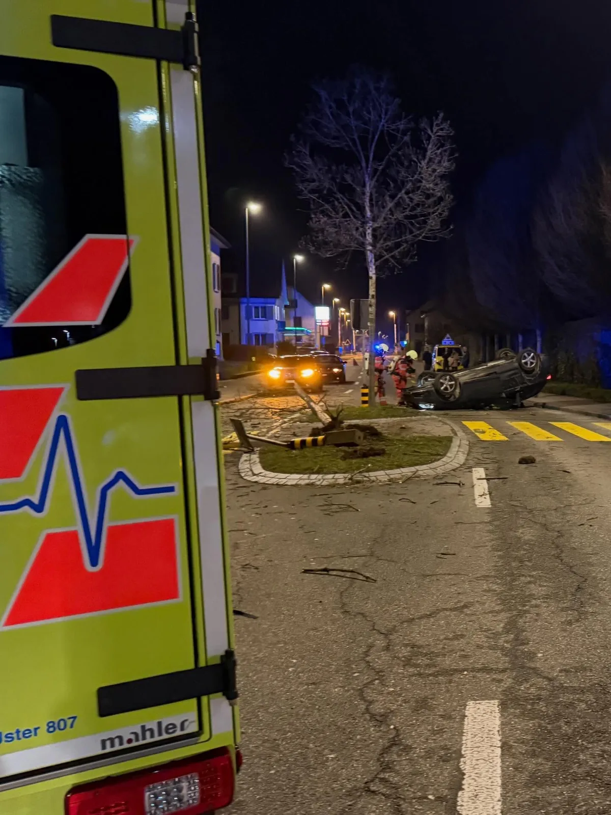Ein dunkles Audi liegt auf dem Dach. Im Vordergrund der nächtlichen Szene sieht man einen Rettungswagen.